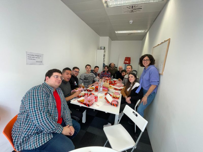 equipo-doonamis-teambuilding-comida Equipo de Doonamis sentados alrededor de una mesa comiendo hamburguesas.